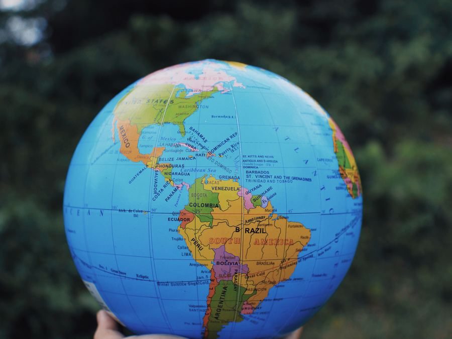 A hand holding up a globe of the world