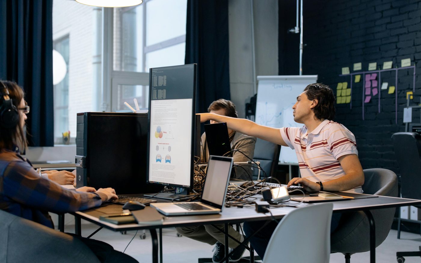 Software developers working together at computer screens in a tech office