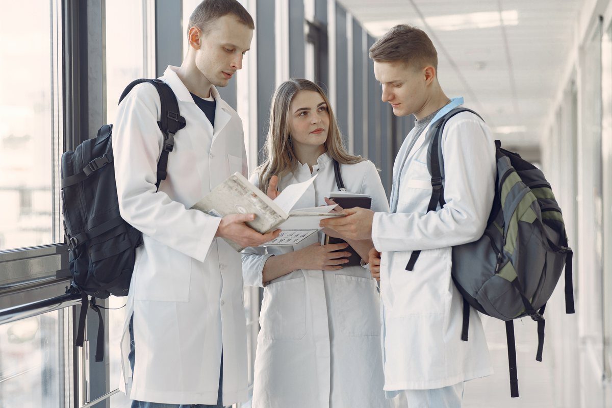Early-career medical professionals reviewing notes together in a bright corridor